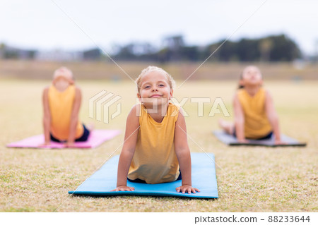 Multiracial elementary schoolgirls doing upward facing dog pose exercise on yoga mat 88233644