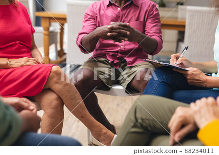 Midsection of multiracial senior men and women discussing during group therapy session Midsection of multiracial senior men and women discussing during group therapy session 88234011