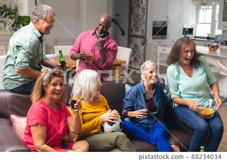 Multiracial senior male and female friends watching soccer match on tv at home 88234034