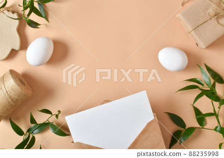 A mock-up of a kraft envelope with a white sheet of paper, eggs and a packed gift. 88235998