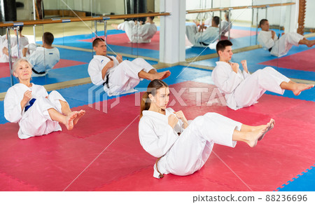 Men and women in kimono doing crunches in gym 88236696