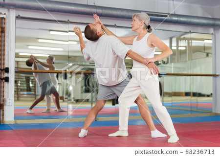 Senior woman performing chin strike during self-defence training 88236713