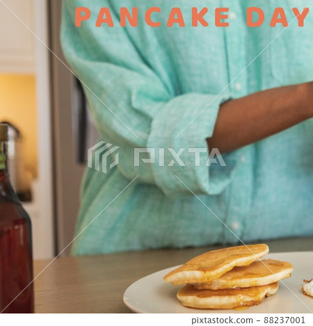 Pancake day text banner against mid section of a person pouring honey over pancakes Pancake day text banner against mid section of a person pouring honey over pancakes 88237001