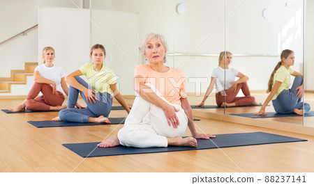 Portrait of woman practicing yoga in group, making twisting asana Portrait of woman practicing yoga in group, making twisting asana 88237141