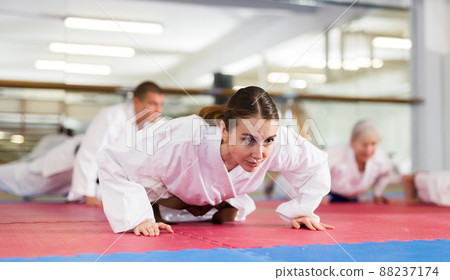 Young woman in kimono doing push-ups in gym 88237174