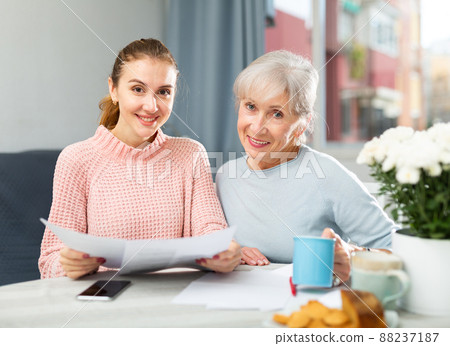Happy elderly woman with adult daughter drinking tea and reading letter 88237187