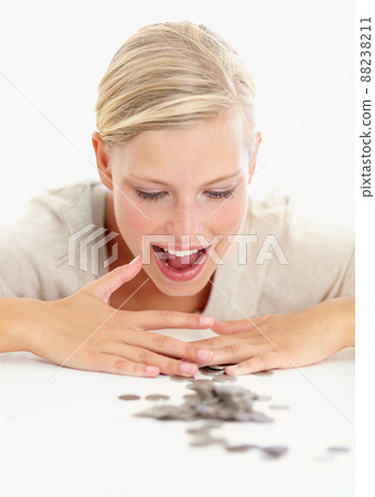 Its all mine. Shot of a beautiful woman looking at coins on the table in front of her. 88238211