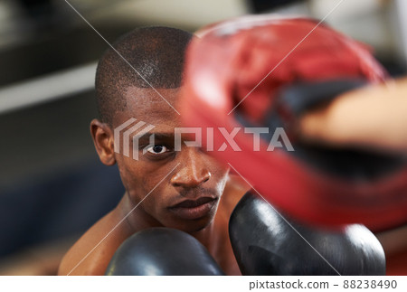 Eyes up here. A young boxer throwing a punch at his partners sparring glove. 88238490