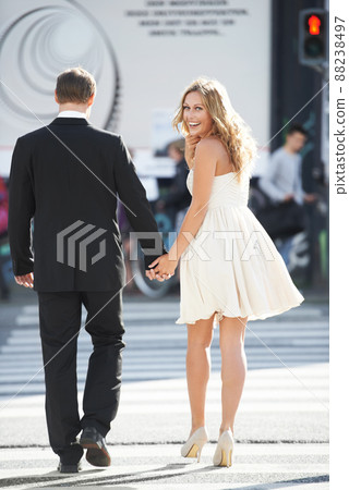 Urban sophistication. A beautiful woman glances back and smiles as she crosses the street with her boyfriend. 88238497