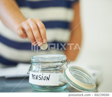 Saving penny for penny. A person putting a penny in a jar that is labeled amp039Pensionamp039. Saving penny for penny. A person putting a penny in a jar that is labeled amp039Pensionamp039. 88239080