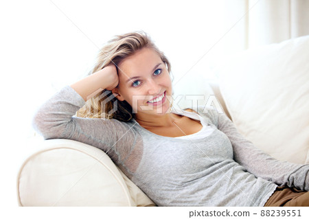 Calm and confident on the couch. Portrait of a young woman relaxing on her couch at home. Calm and confident on the couch. Portrait of a young woman relaxing on her couch at home. 88239551