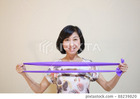 Middle-aged woman doing muscle training with a rubber band Middle-aged woman doing muscle training with a rubber band 88239820