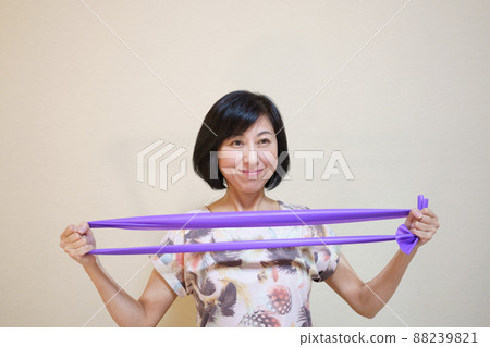 Middle-aged woman doing muscle training with a rubber band Middle-aged woman doing muscle training with a rubber band 88239821