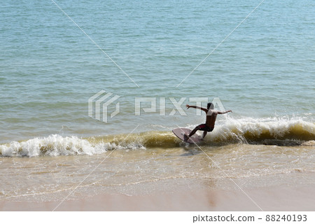 Man on a skimboard catching a wave in a beach in Aonang, Krabi, Thailand 88240193