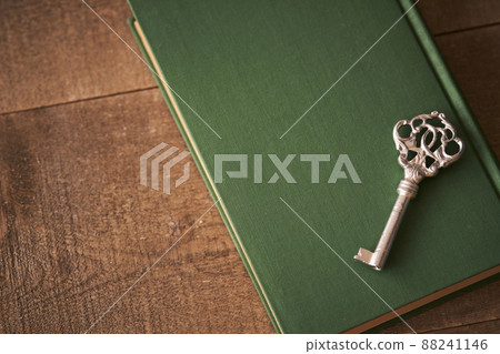 A silver key placed on an old book 88241146