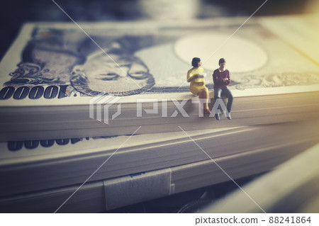 Miniature men and women sitting on banknotes Miniature men and women sitting on banknotes 88241864