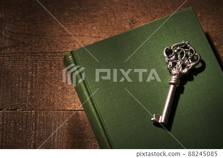 A silver key placed on an old book 88245085