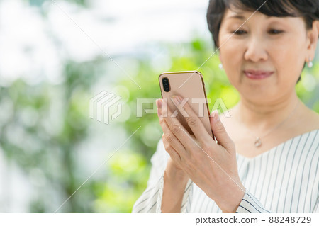 新鮮的綠色資深婦女微笑智能手機 88248729