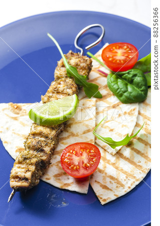 herbal meat skewer  with pita bread, tomatoes and lime 88256366