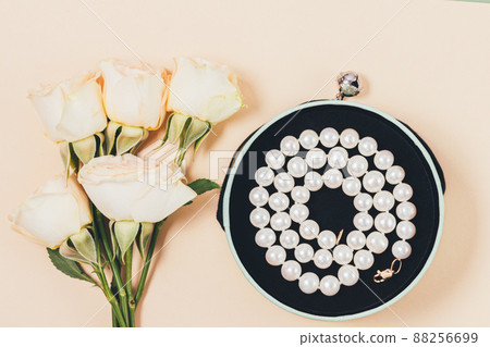 Romantic gift pearl necklace next to bouquet of roses Romantic gift pearl necklace next to bouquet of roses 88256699