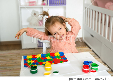 World Autism Awareness day concept. Drawing for the day of World Autism Day and painting puzzles and hearts with a brush and paints. A girl draws a drawing for autism day 88257120