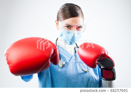 Young female caucasian doctor wearing blue uniform and red boxing gloves 88257691