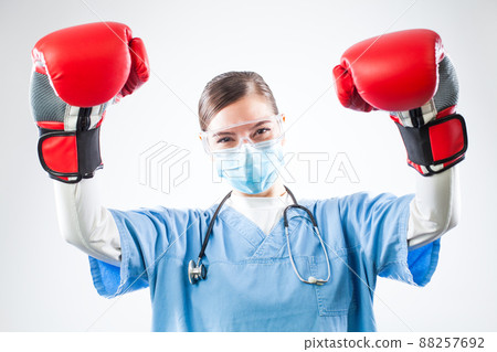 Victorious young female caucasian GP doctor wearing blue uniform red boxing gloves 88257692