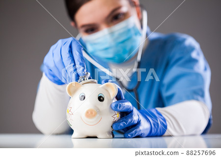 Doctor inspecting piggy bank with stethoscope 88257696