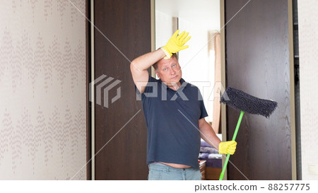 A single blond man washes the floors in his house A single blond man washes the floors in his house 88257775