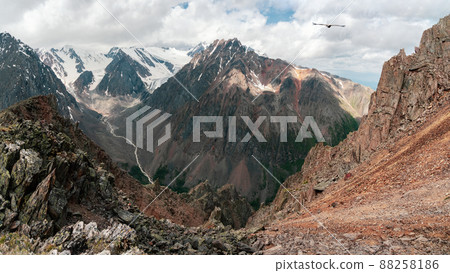 Dangerous couloir. Panoramic colorful sunny green landscape with silhouettes of big rocky mountains and epic deep gorge. Picturesque mountain valley. Dangerous couloir. Panoramic colorful sunny green landscape with silhouettes of big rocky mountains and epic deep gorge. Picturesque mountain valley. 88258186
