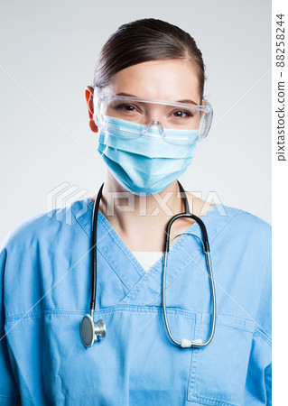 Happy satisfied female doctor wearing protective face mask & safety goggles Happy satisfied female doctor wearing protective face mask & safety goggles 88258244