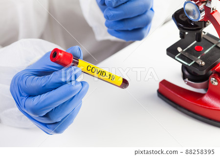 Lab scientist or medical technologist holding a yellow COVID-19 test tube blood sample vacutainer 88258395