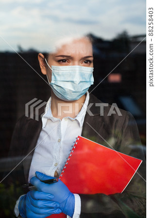 Young anxious caucasian business woman looking through office window 88258403