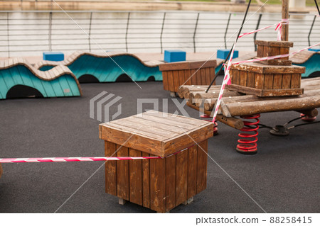 Chairs and benches in a park wrapped in red protective barrier tape Chairs and benches in a park wrapped in red protective barrier tape 88258415