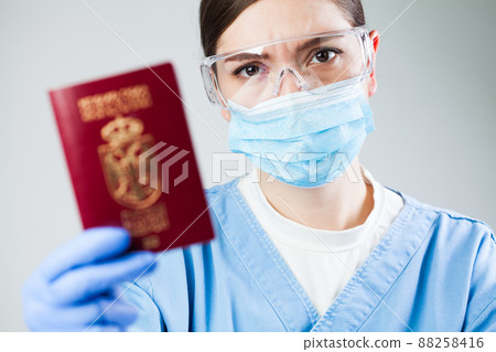 Doctor or nurse at airport customs security check holding a passport Doctor or nurse at airport customs security check holding a passport 88258416
