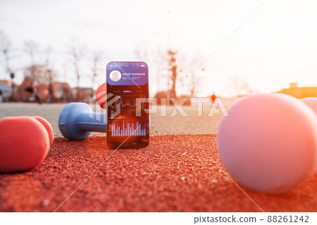 Health app. Smart phone screen with fitness health or sport gym mobile application on dumbbell background. Home online workout. Health app. Smart phone screen with fitness health or sport gym mobile application on dumbbell background. Home online workout. 88261242