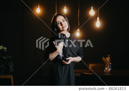 attractive brunette woman with French Bulldog puppy in dark loft-style apartment 88261813