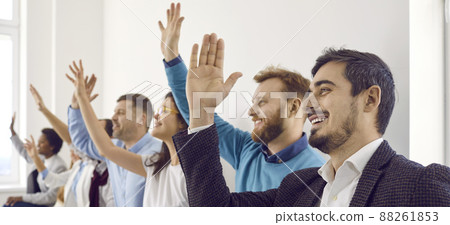 Group of happy people raising their hands up to ask questions at business conference 88261853