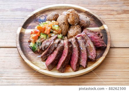 Lightly fried piece of cow meat for lovers with salad and baked potatoes. On a wooden background and a plate 88262300