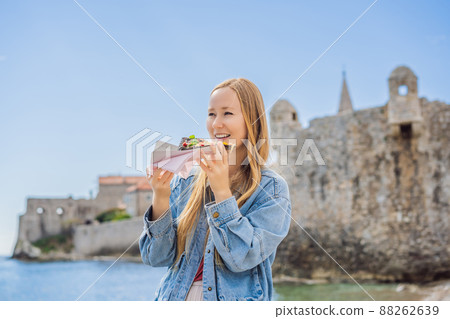 Young woman tourist eating traditional pizza in the old town of Budva. Travel to Montenegro concept 88262639