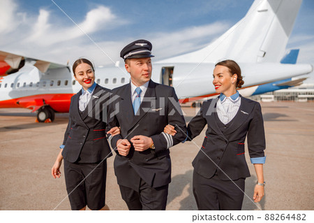 Aircraft pilot and flight attendants walking down airfield Aircraft pilot and flight attendants walking down airfield 88264482