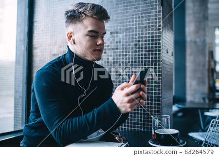 Thoughtful man text messaging in cafe Thoughtful man text messaging in cafe 88264579