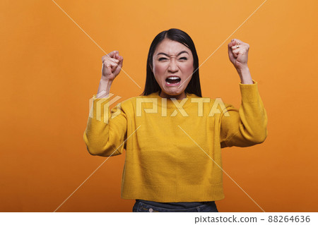 Mad furious asian woman angered and annoyed by loud music heard from neighbors. Upset frustrated person aggressively yelling while having a quarrel with friend about rage conflict and stress. 88264636