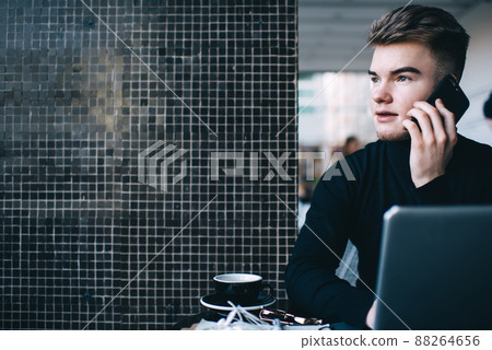 Concentrated man looking away while talking on phone 88264656