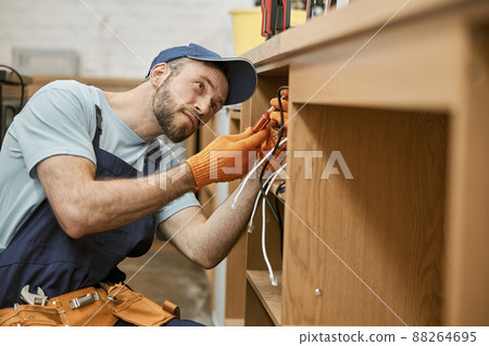 Bearded male electrician repairing desk electrical cable 88264695
