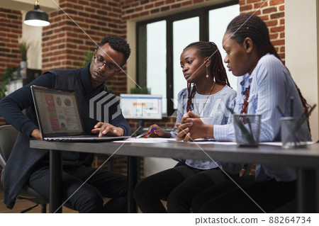 Marketing company worker presenting coworkers work policy and new annual expenses budget. Development department african american team leader informing employees about business plan. Marketing company worker presenting coworkers work policy and new annual expenses budget. Development department african american team leader informing employees about business plan. 88264734