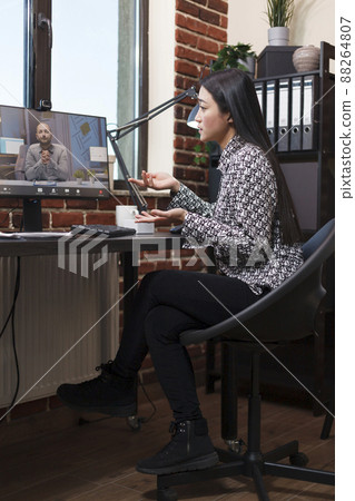 Marketing agency employee sitting at work computer while in online remote videocall conference with team colleague. Businesswoman briefing coworker about failed strategy and unfinished presentation Marketing agency employee sitting at work computer while in online remote videocall conference with team colleague. Businesswoman briefing coworker about failed strategy and unfinished presentation 88264807