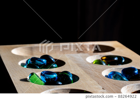 Selective focus on glass beads on a wooden mancala board Selective focus on glass beads on a wooden mancala board 88264922