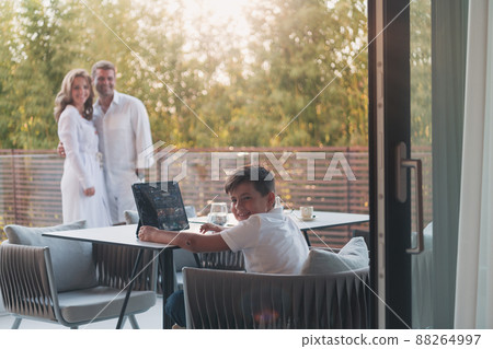 Happy elderly couple resting on the balcony of a luxury house while their son using a tablet. Selective focus 88264997