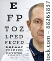 Portrait of an ophthalmologist with a closed eye to check the sharpness of vision. 88265837